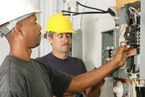 Two licensed electricians working on a residential electrical panel